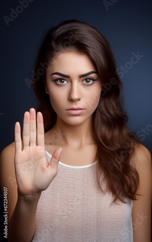 A young woman makes the stop gesture with her hand raised in front of her