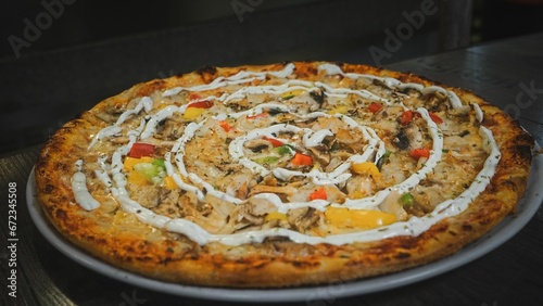 Delicious chicken BBQ pizza with a variety of toppings and a drizzle of cream on a metal tray