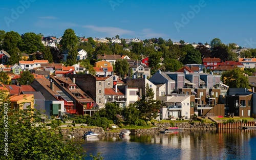 Cozy buildings of a small town at the waterfront surrounded by lush vegetation © Wirestock