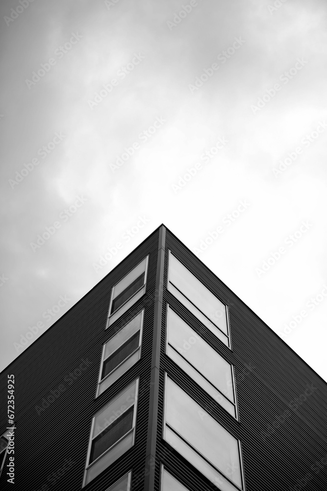 Low angle view of a tall, multi-story building in a bustling city in grayscale Low angle view of a tall, multi-story building in a bustling city in grayscale