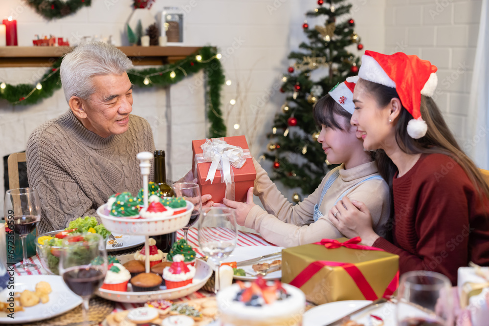 Asian granddaughter gives a Christmas gift to her grandfather Asian granddaughter gives a Christmas gift to her grandfather