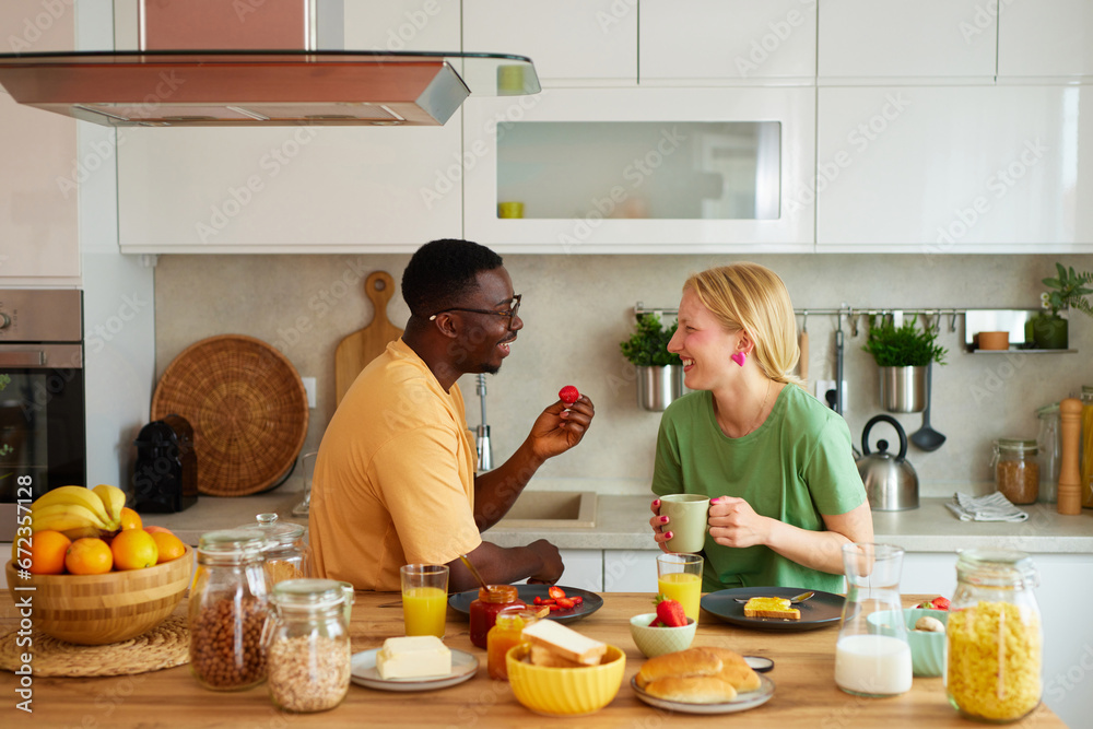 Multiracial couple enjoying breakfast together at home