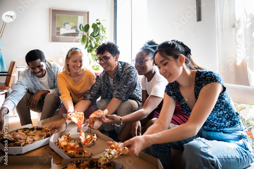 Young diverse friends having pizza at home photo