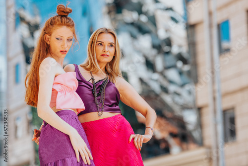 Obraz na plátně Two fashionable women confidently wander through the city, showcasing their well-dressed style