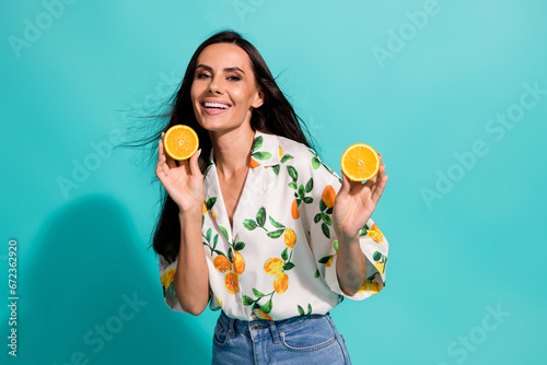 Portrait of nice woman with straight hairdo dressed flower print blouse showing sliced orange isolated on turquoise color background
