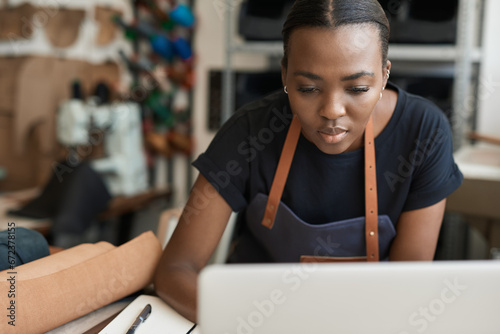 African female leather worker using a laptop in her workshop