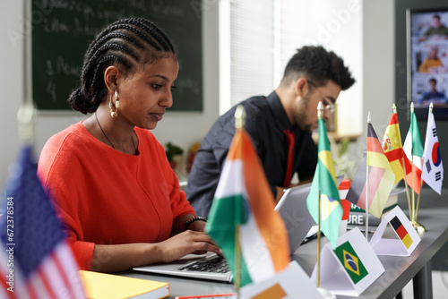 Canvastavla Group of international students sitting at table with flags and using gadgets at