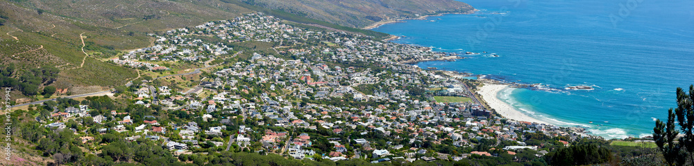 Panoramic landscape of a large city on the coast from above. Beautiful scenic and aerial view of a popular tourist town or residential area with greenery and the ocean in nature during summer
