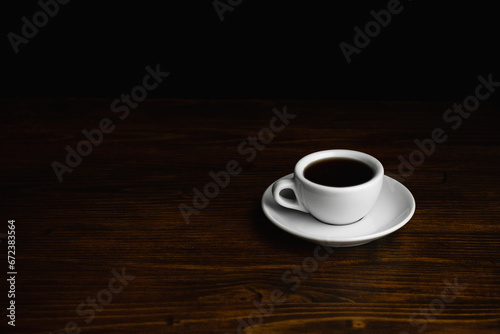 White Cup of black coffee on a wooden table. Copy space