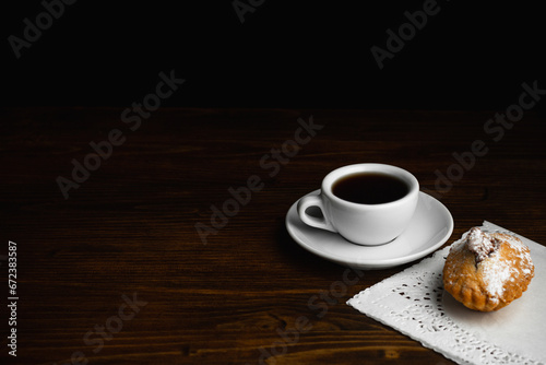 Muffin with white cup of coffee on a dark wooden background