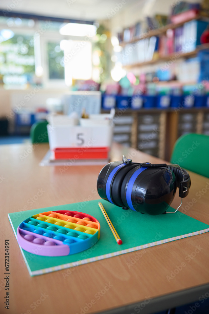 Fototapeta premium Ear Defenders Or Headphones And Fidget Toy To Help Child With ASD Or Autism On Table In School Classroom