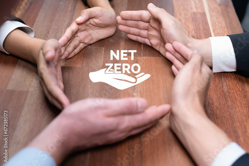 Top view group of business people forming circle hand around eco-friendly net zero icon on meeting table. Alternative clean technology technology investment for greener sustainable future. Quaint
