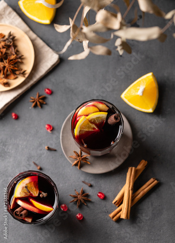 Mulled wine with orange, apple and cinnamon in glasses on a dark background. The concept of a traditional winter hot drink with spices and fruits for the holiday.