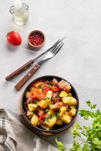 Wallpaper Mural Fried pork meat with potatoes, onions and peppers. National homemade Georgian dish ojakhuri in a black bowl on a light background with fresh herb, spices and tomato. Torontodigital.ca
