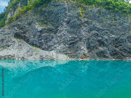 .Aerial view beautiful The reflection of the blue sky in the emerald green pond..Emerald green pond at an old mine..Pine trees line the side of an emerald green pond..blue water blue sky background.