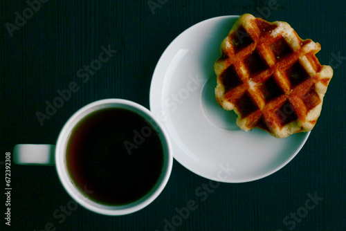 Breakfast for one. Belgian waffle and cup of coffee. View from above. Dark background.