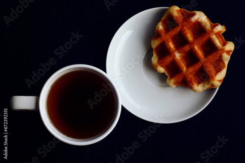 Breakfast for one. Belgian waffle and cup of coffee. View from above. Dark background.