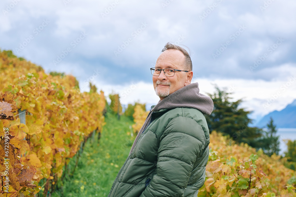 Outdoor portrait of middle age 55 - 60 year old man enjoing nice autumn day in vineyards, healthy and active lifestyle