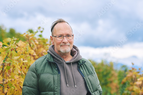 Outdoor portrait of middle age 55 - 60 year old man enjoing nice autumn day in vineyards, healthy and active lifestyle photo