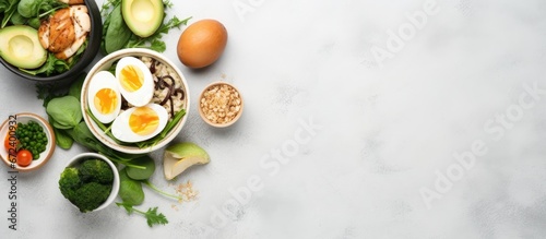 Clean and healthy food composed of dark rice eggs avocado spinach and chicken slices are served in ceramic bowls on a light grey background The ingredients used are organic and natural The 