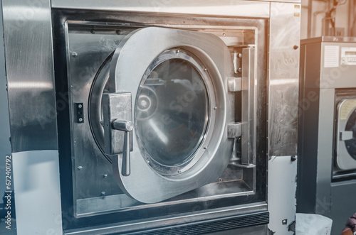 Automatic washing machine in the dry cleaning room. Close-up view of the washing machine door. © romankrykh