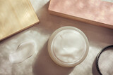 Cosmetic cream glass jar and swatch on background with lace shadow. Soft nude blush powder beige style