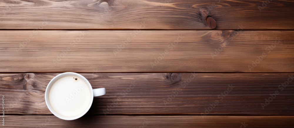 A wooden desk in an office holds a coffee cup along with a notebook and paper A wooden desk in an office holds a coffee cup along with a notebook and paper