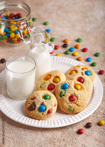 American cookies with colorful chocolate candy drops served with glass of milk. Delicious homemade dessert for children.