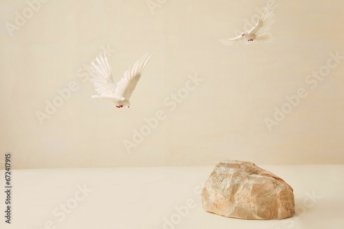 White doves soaring gracefully above a large, stone with a white background
