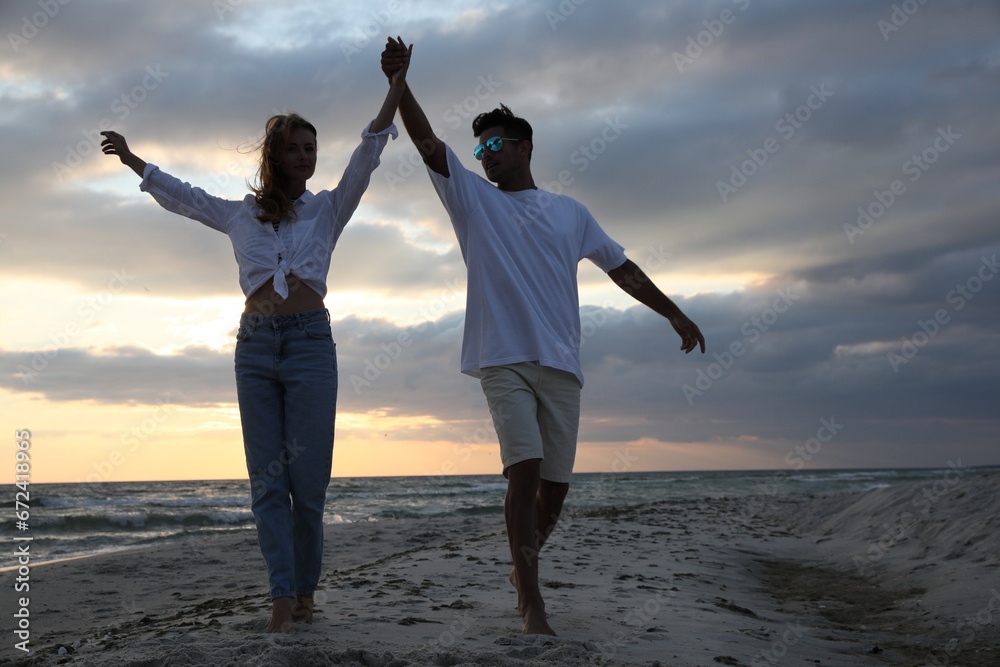 Fototapeta premium Happy couple dancing on beach at sunset