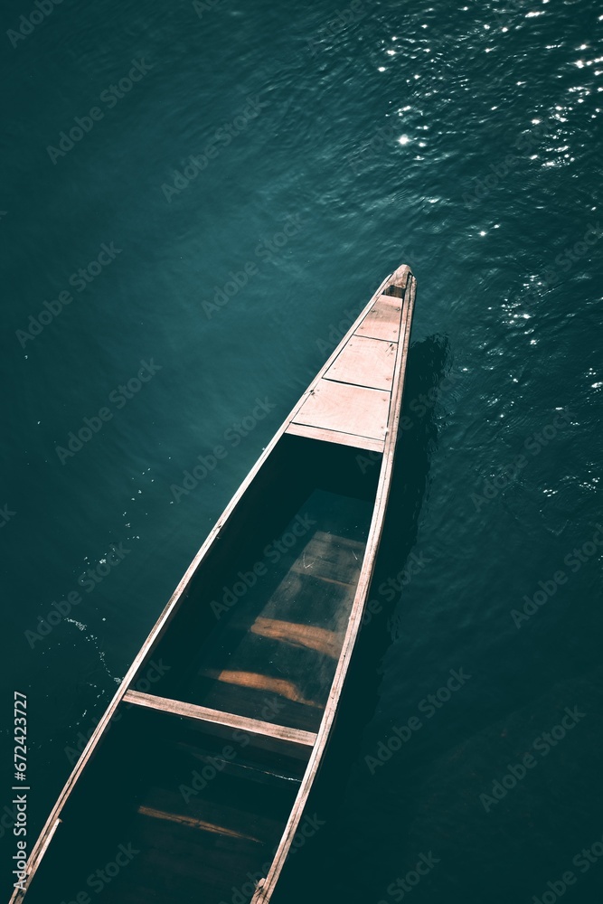 Vertical high angle shot of a wooden canoe floating in a large body of water