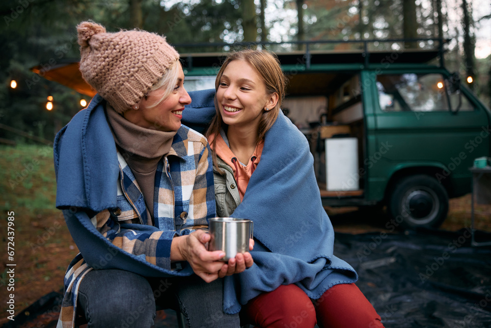 Happy mother and daughter talk while relaxing at camper trailer park. - obrazy, fototapety, plakaty 