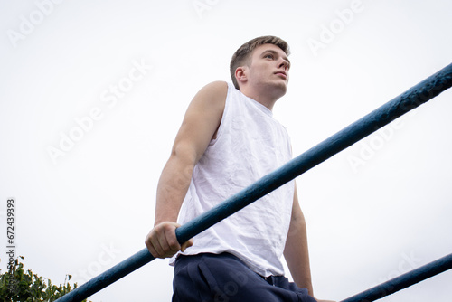 A cute young man doing exercises on the uneven bars at the stadium