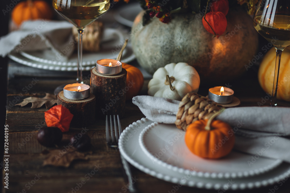 Cozy festive holiday table decor for home family Thanksgiving dinner. Traditional event, elegant natural decoration. Wooden rustic table, countryside style. Burning candles, floral centrepiece pumpkin