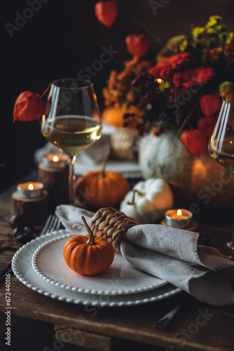 Cozy festive holiday table decor for home family Thanksgiving dinner. Traditional event  elegant natural decoration. Wooden rustic table  countryside style. Burning candles  floral centrepiece pumpkin