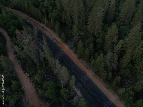 Aerial view of a train track passing through lush green forest at dusk