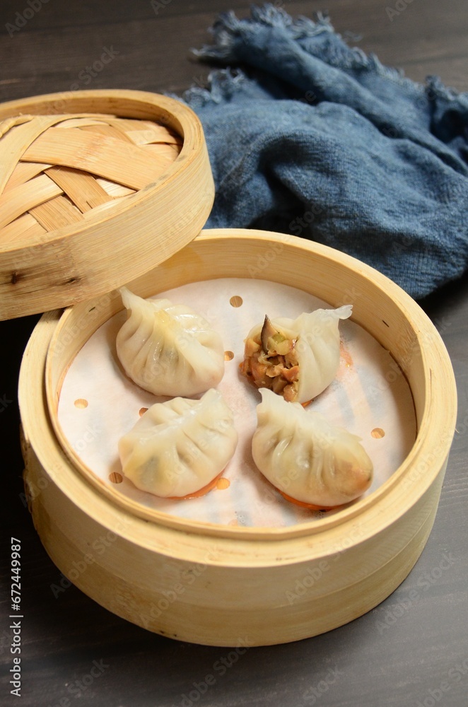 A small wooden container on a table with dumplings inside it A small wooden container on a table with dumplings inside it