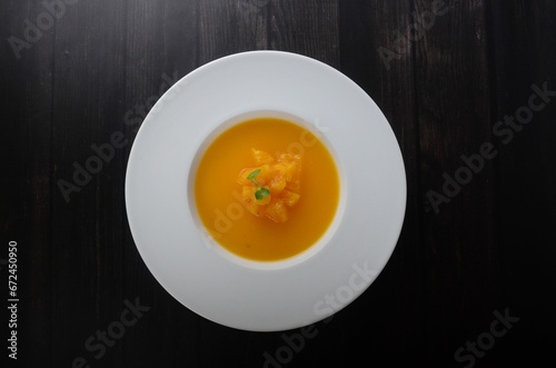 Closeup of a ceramic bowl filled with hearty pumpkin soup.