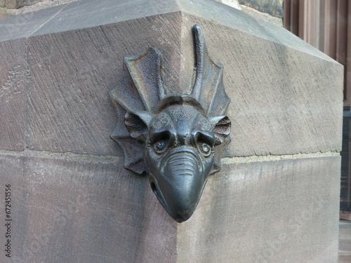 Antique bronze dragon head sculpture is affixed to the exterior wall of a building.