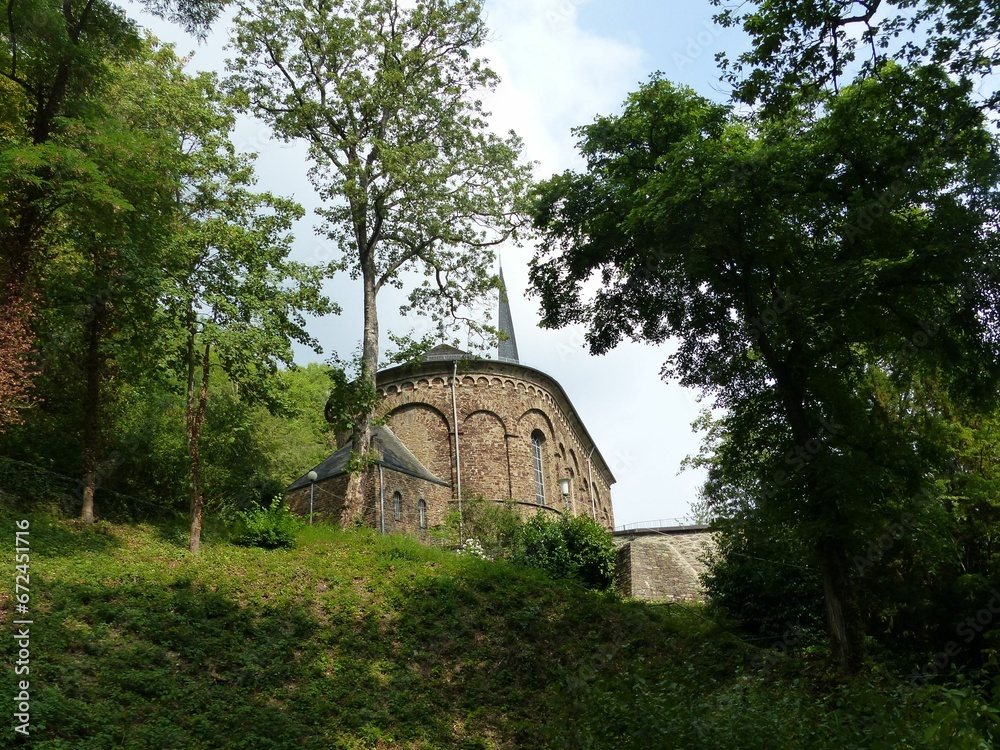an old stone church sitting among green trees in the mountains