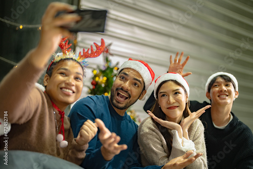 Party of asian Friends Enjoying Christmas Drinks and celebrating having selfie by smartphone. happiness women and man christmas eve celebrate dinner with food and beverage.