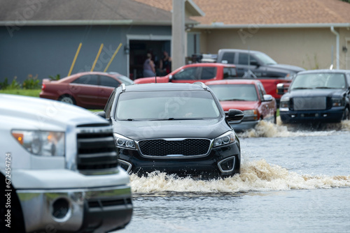 Flooded street after hurricane rainfall with driving cars in Florida residential area. Consequences of natural disaster