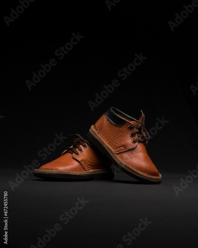Pair of high-quality brown leather shoes in dark background.