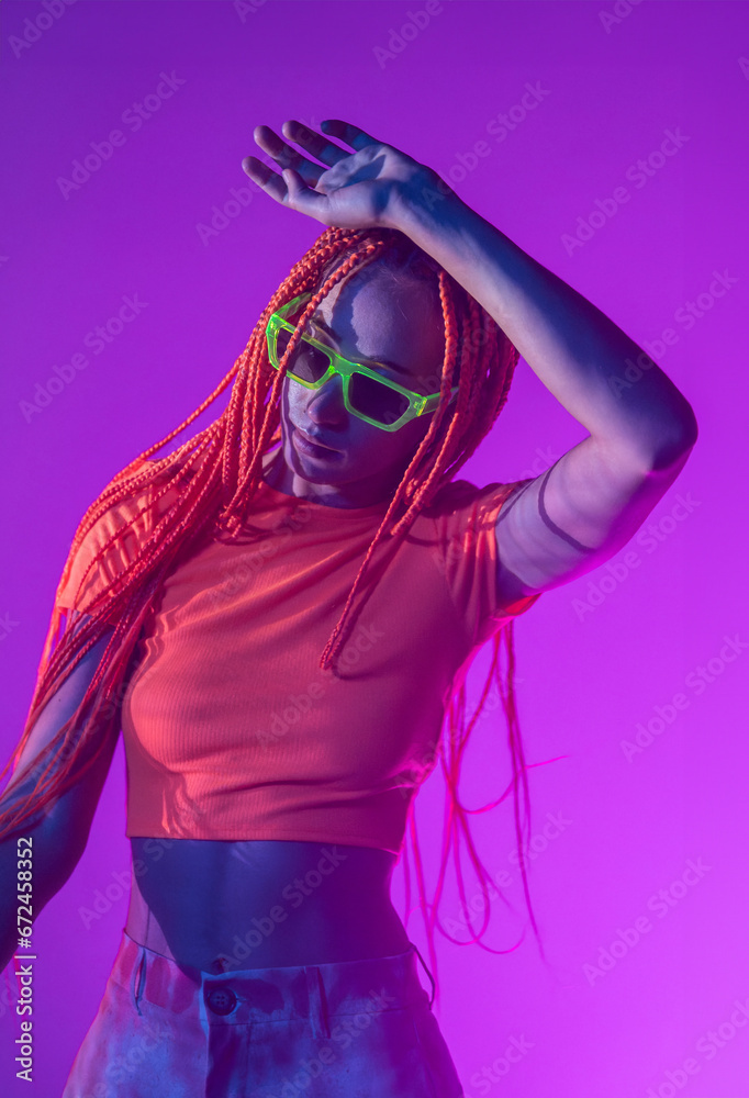 Woman with orange braids standing in neon lights Woman with orange braids standing in neon lights