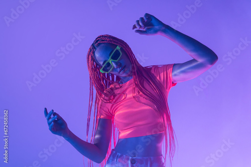 Woman with orange braids standing in neon lights photo