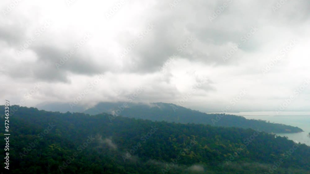 Clouds above mountains covered in rainforest with green trees Clouds above mountains covered in rainforest with green trees