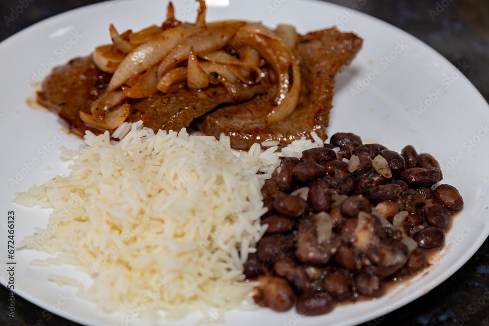 The most traditional Brazilian lunch dish, black beans, rice and onion steak The most traditional Brazilian lunch dish, black beans, rice and onion steak