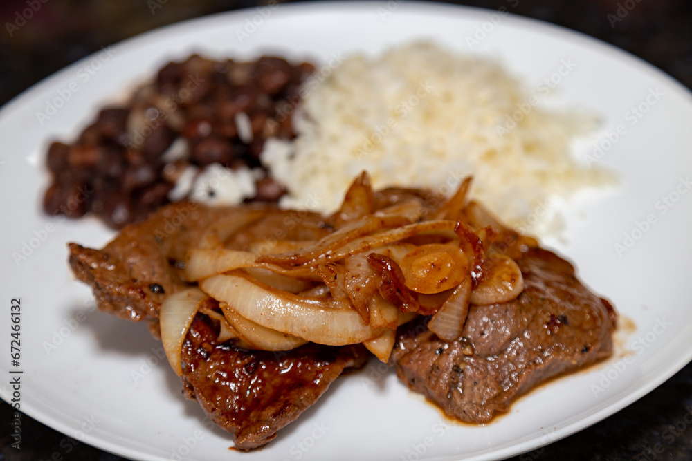 The most traditional Brazilian lunch dish, black beans, rice and onion steak