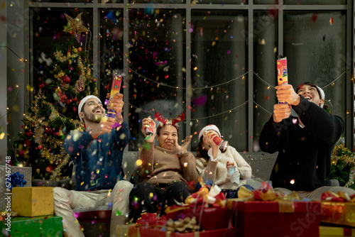 men and women using paper shoot in a party at living room. young couple Asian people enjoy celebrating Christmas and New Year. happy and celebrate with gift and presents.