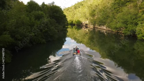 Boat in aerial view sailing on the river with nature greenery and blue sky